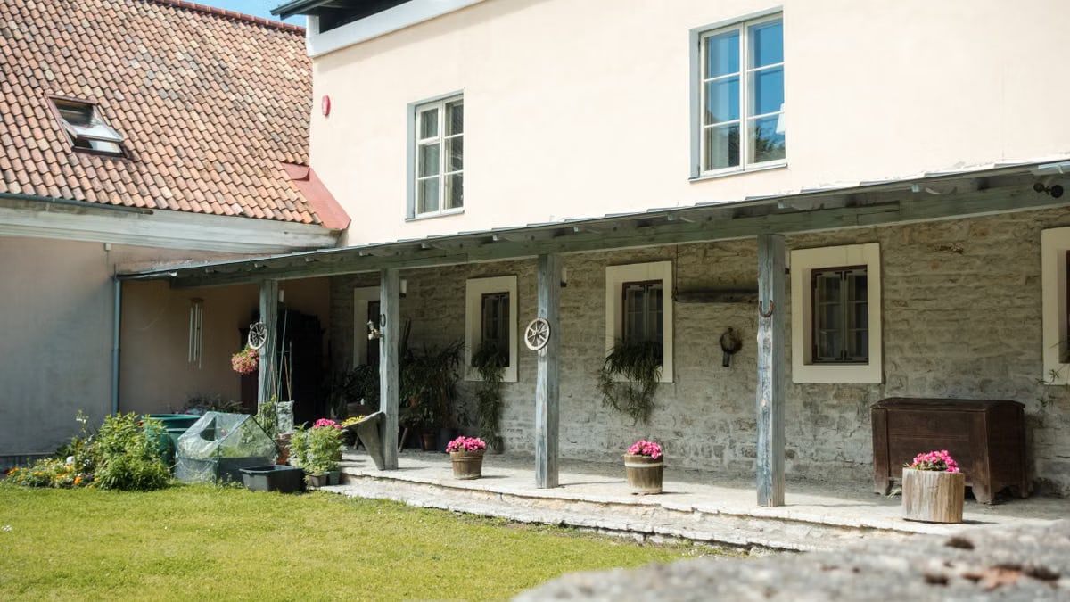 A quaint house in Tallinn with a rustic porch and vibrant potted flowers, showcasing traditional architecture.
